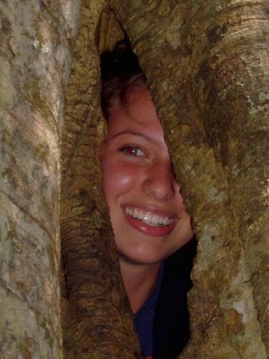 Face peering through gap in tree
