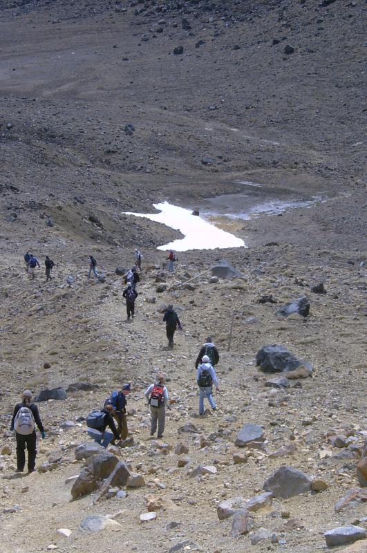  Hikers moving across flat, bouldered terrain