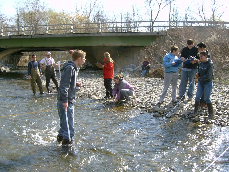 Students in stream with tape measures