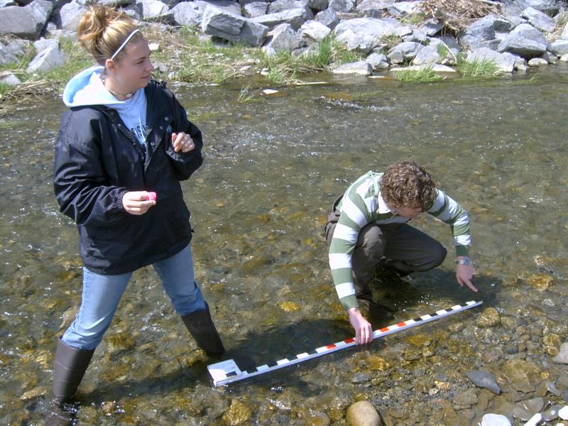 Student in waders measuring stream depth