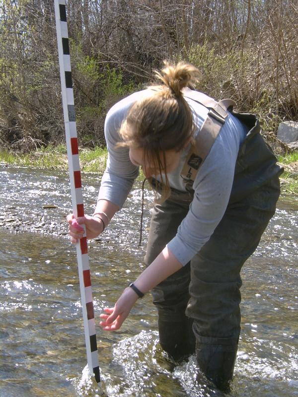 student with meter flagstaff in stream