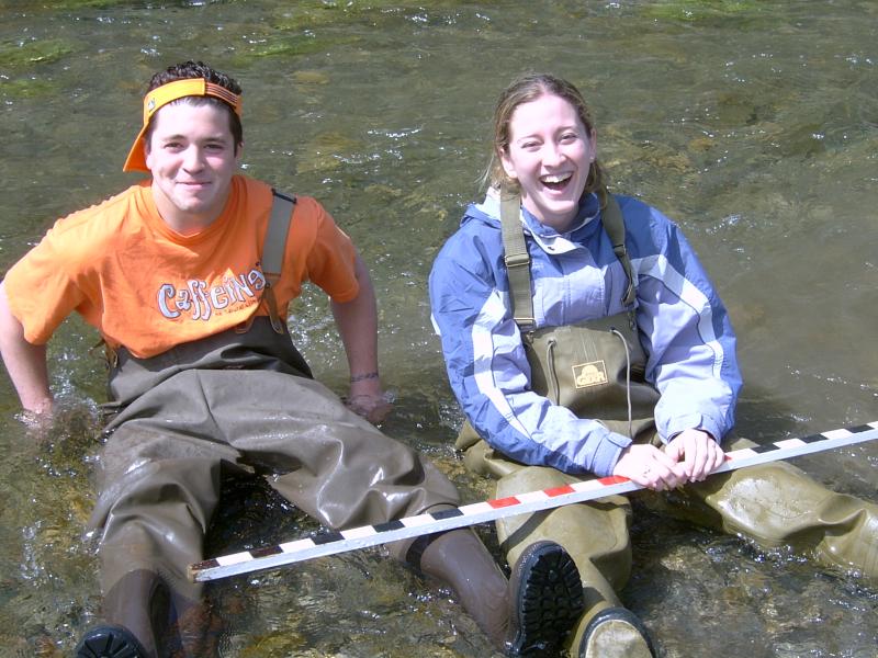 students in waders sit in the stream